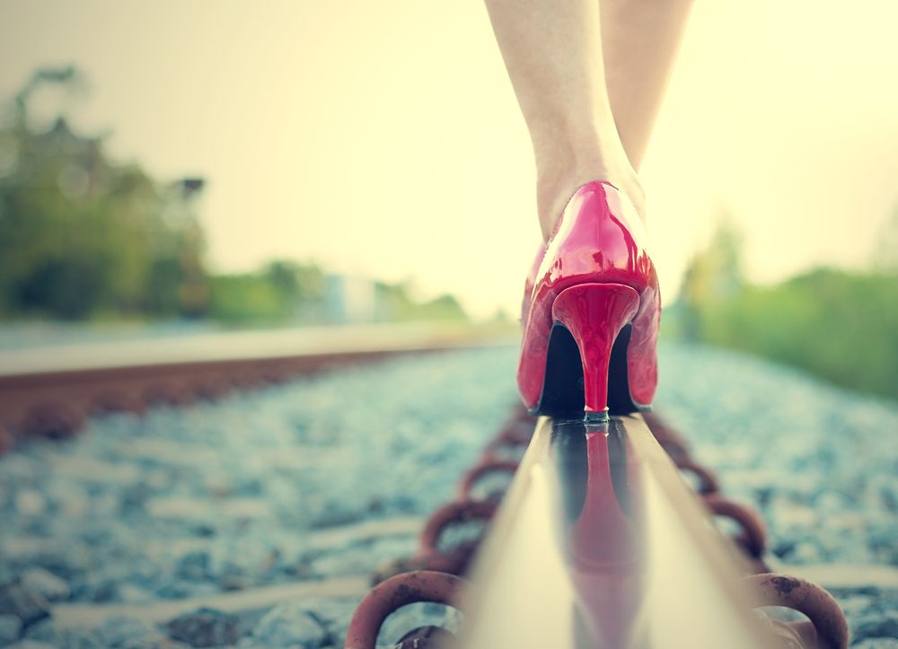 mujer caminando en tacones sobre la vía del tren