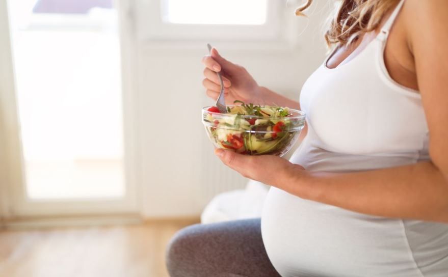Mujer embarazada comiendo verduras